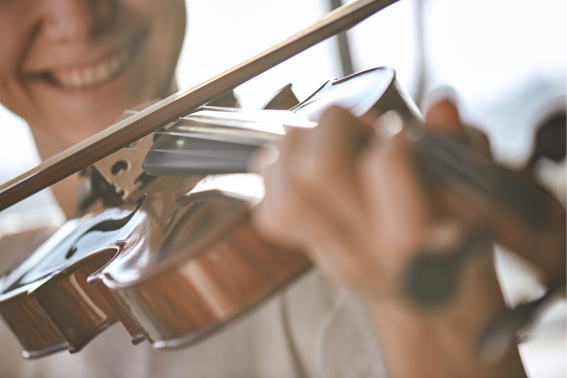 Nahaufnahme eines lächelnden Geiger, der klassisch Musik auf dem Braun spielt