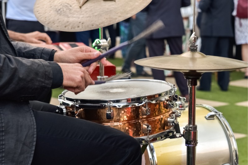 männlicher Musiker spielt Schlagzeug und Becken bei Konzert