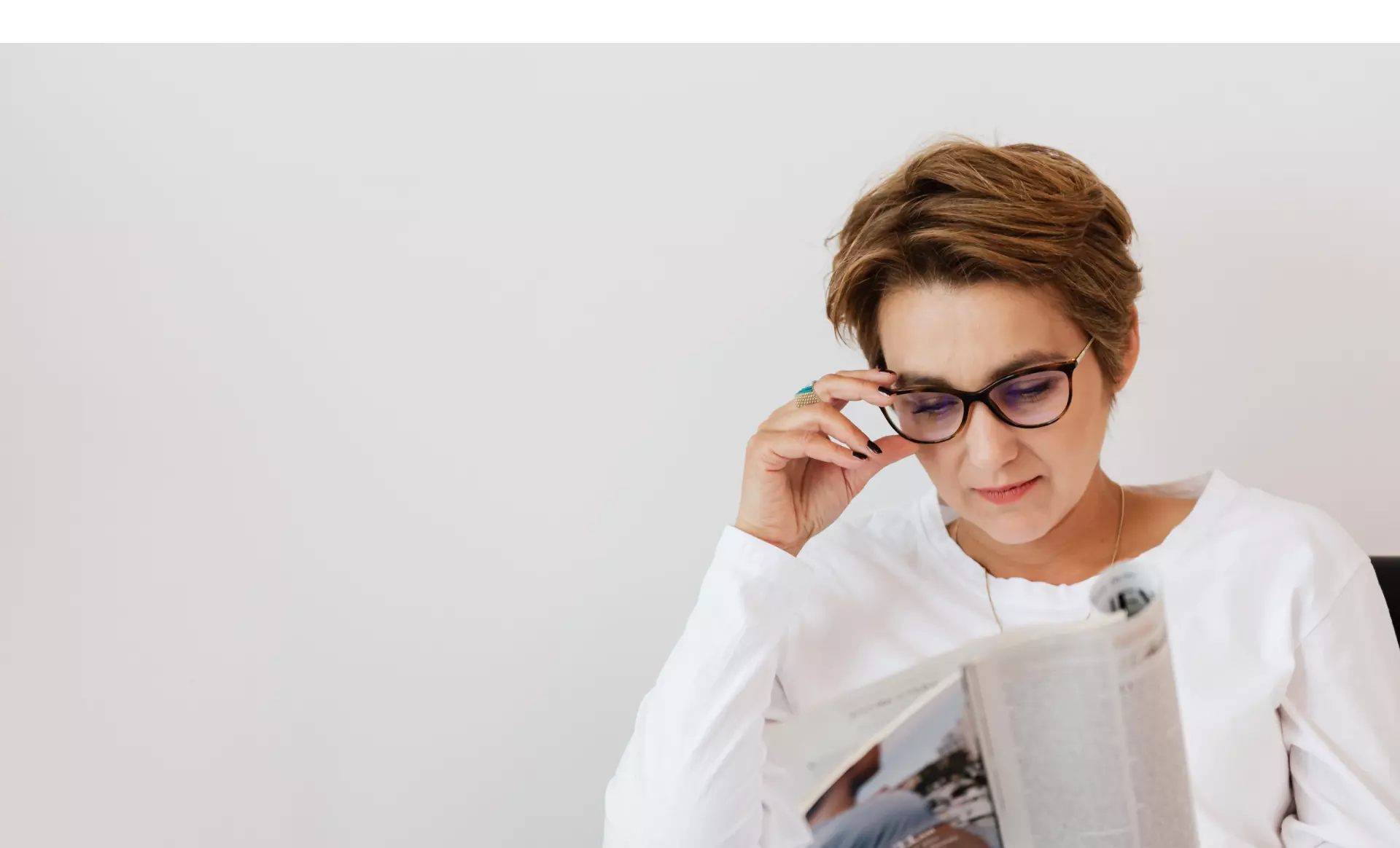 Frau mit Brille liest gemütlich einen Zeitschrift