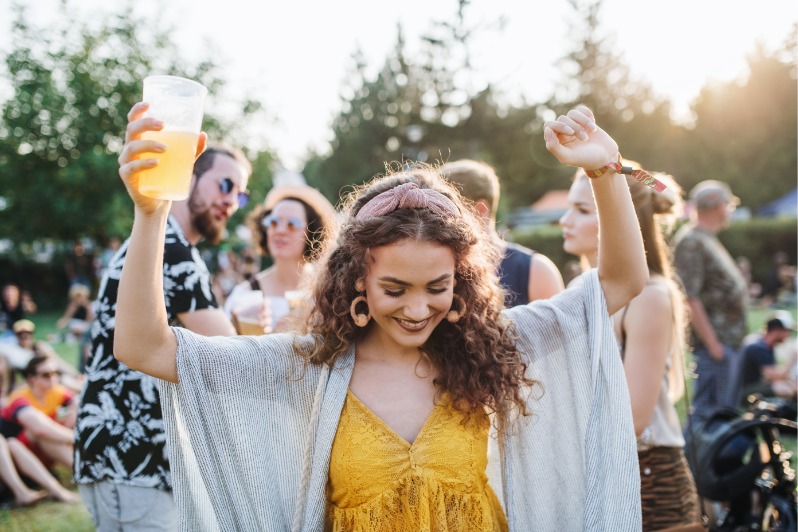 Eine junge Frau mit Drink tanzt auf Sommerfest