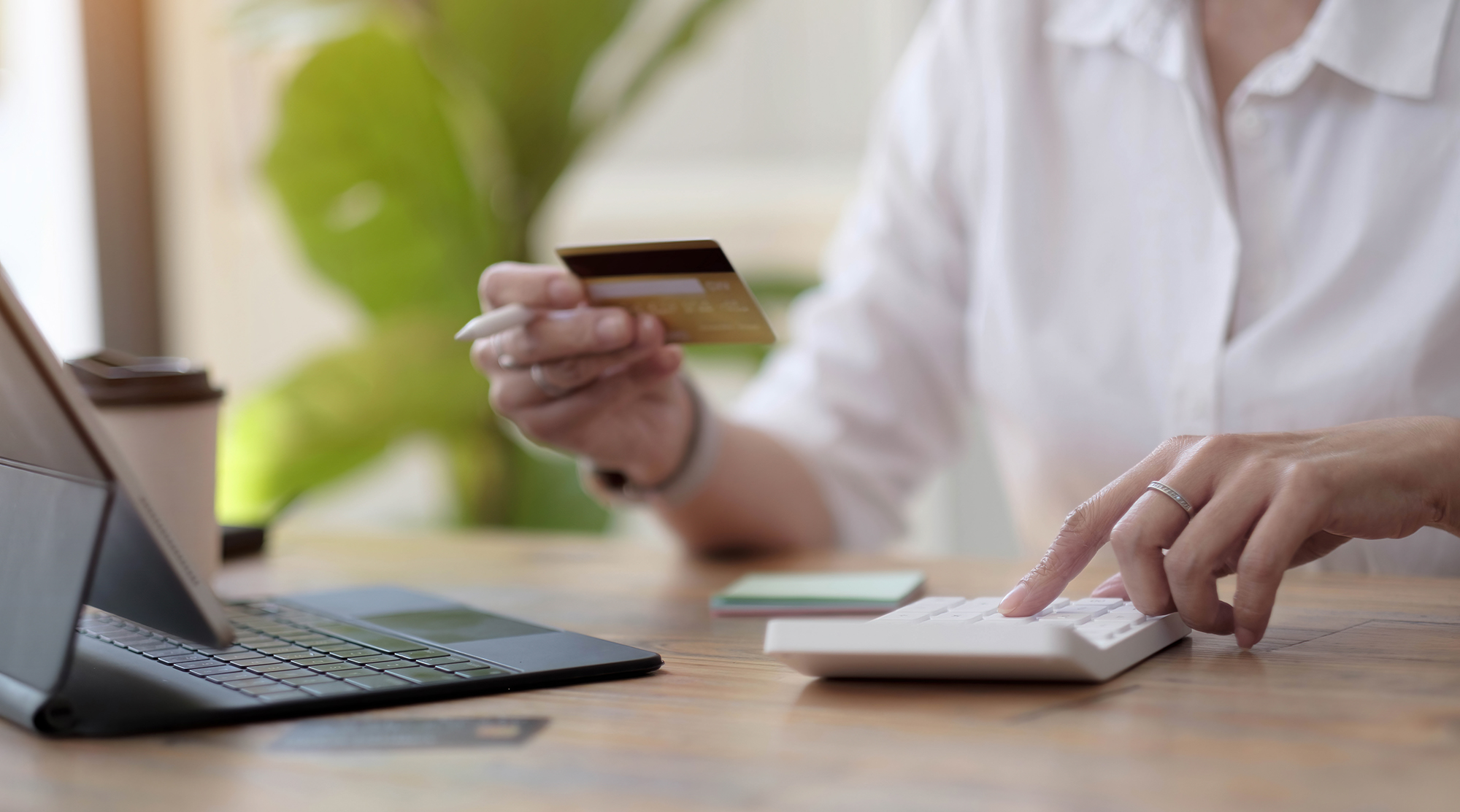 Frau macht Berechnungen und kauft online mit Kreditkarte ein. Frau nutzt Taschenrechner